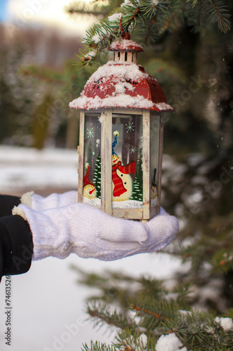 Beautiful red decorative Christmas lantern on warm mittens