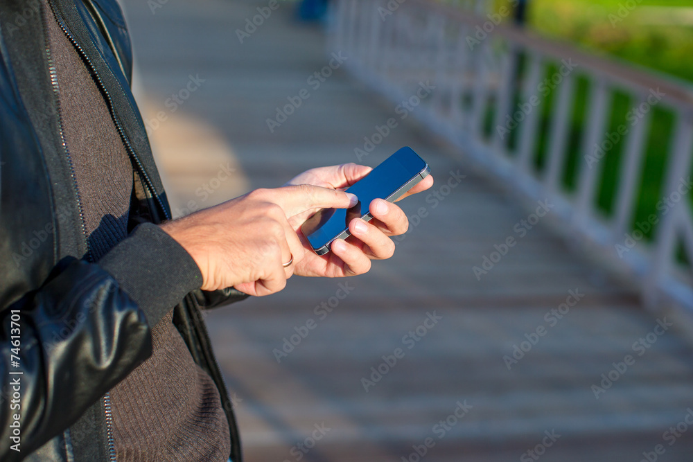 Closeup man's hands using mobile phone outdoors
