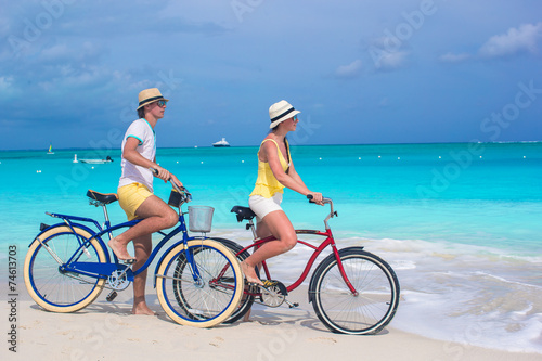 Young happy couple riding bikes on white tropical beach photo