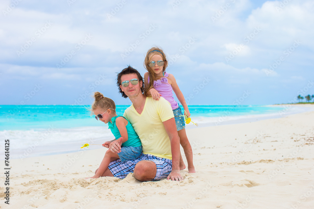Adorable little girls and happy dad on tropical white beach