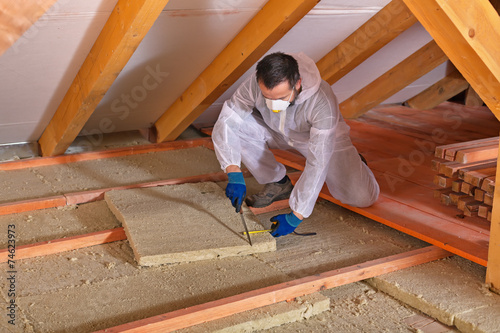 Man laying thermal insulation layer - cutting the panels