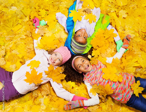 Kids play with autumn maple orange leaves photo