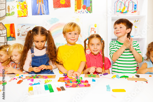 Happy boys and girls with plasticine in classroom