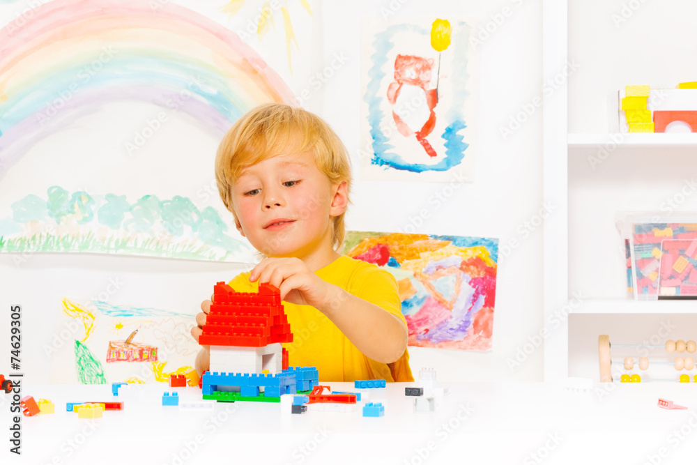 Handsome blond boy playing with plastic blocks Handsome blond boy playing with plastic blocks