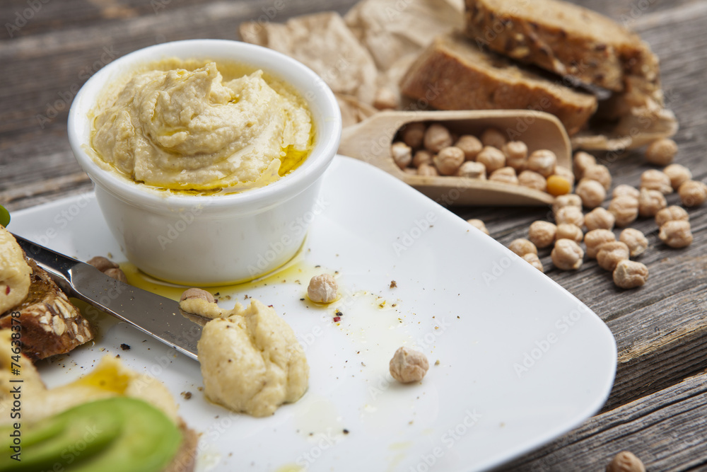 The composition of hummus on a wooden table The composition of hummus on a wooden table