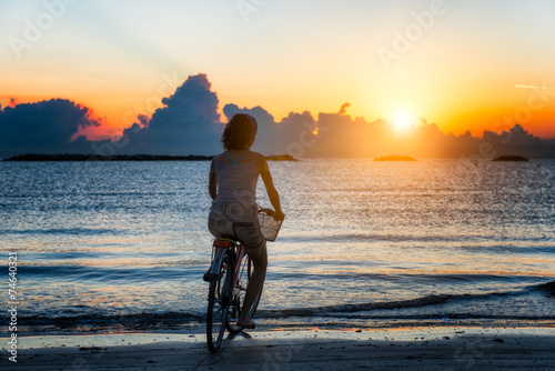 Girl cycling in the sea during sunrise © michelangeloop