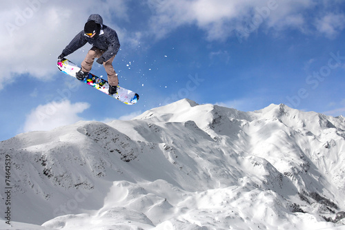 Jumping snowboarder through air on blue sky background