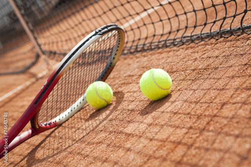 Close up of tennis racquet and balls on the clay tennis court 