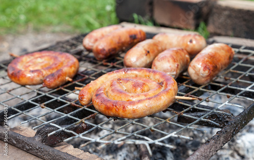 Tasty sausages cooking over the hot coals on a barbecue fire