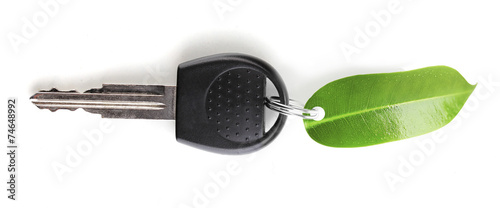 Car key with green leaf trinket isolated on white photo