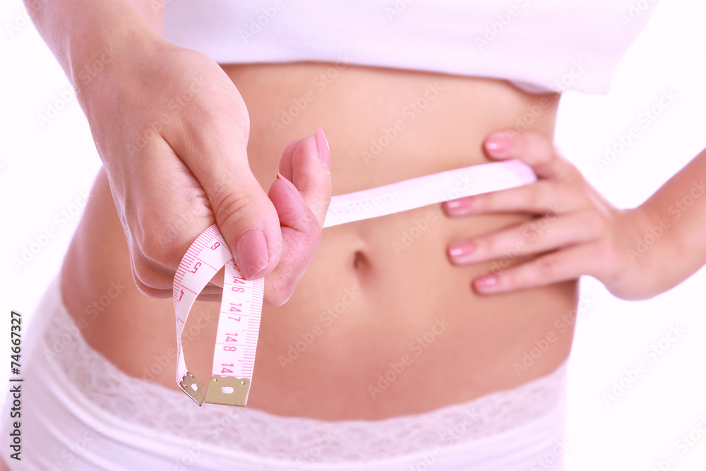 A slim girl measuring her waist, closeup, isolated on white A slim girl measuring her waist, closeup, isolated on white