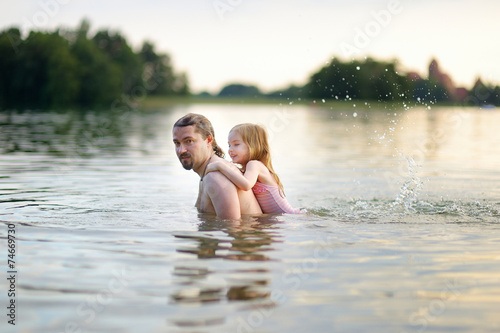 Little girl and her father having fun in a river