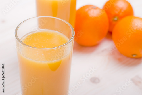 Orange fresh juice beside delicious ripe oranges on the table