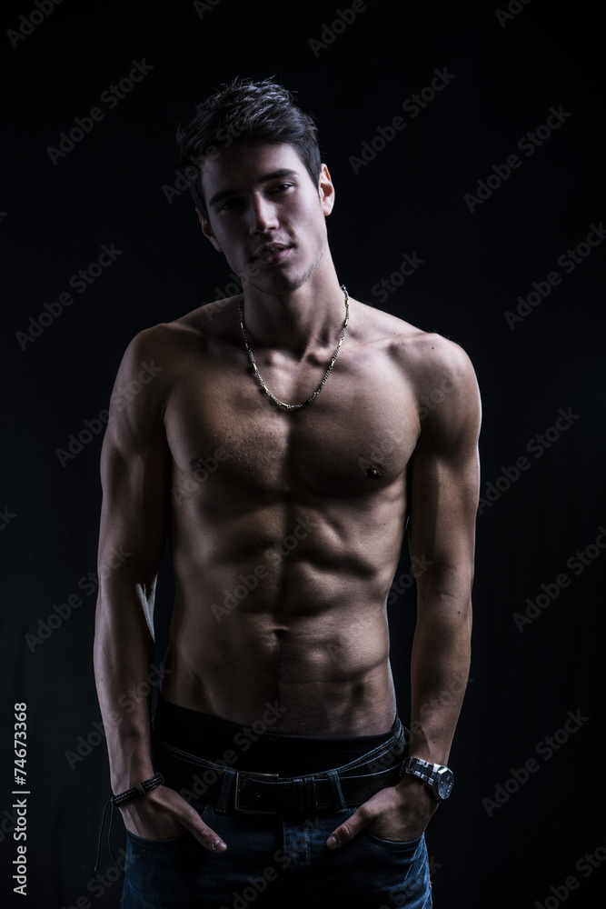 Handsome muscular shirtless young man standing confident