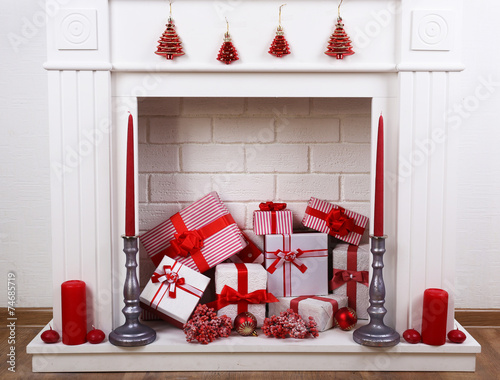 Fireplace with Christmas boxes and candles on wooden floor photo