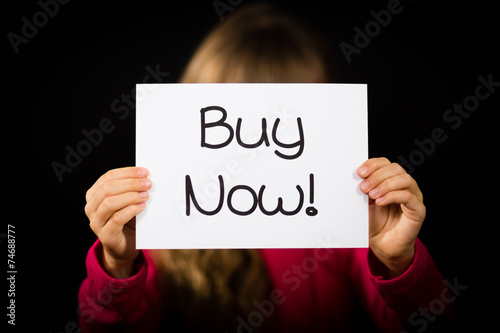Child holding Buy Now sign
