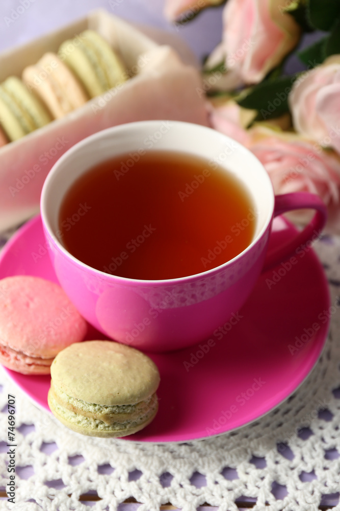 Colorful macaroons with cup of tea on wooden background Colorful macaroons with cup of tea on wooden background