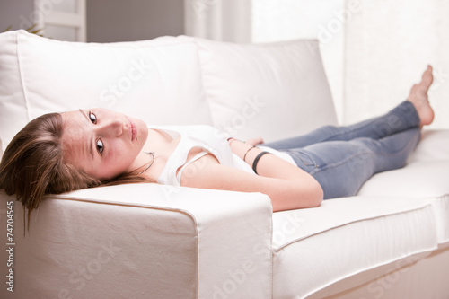 girl looking you and smiling while lying on a sofa