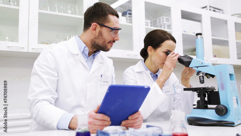 scientists with tablet pc and microscope in lab scientists with tablet pc and microscope in lab