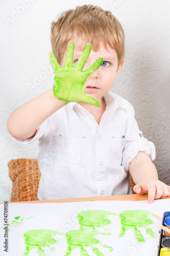 Funny child having fun with making handpaints photo