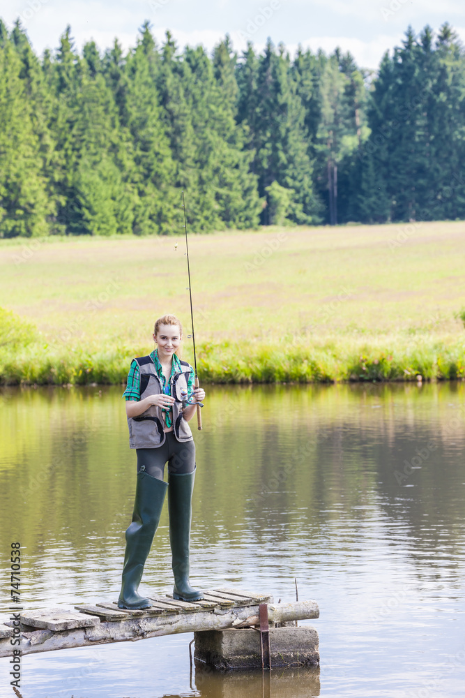 young woman fishing on pier at pond young woman fishing on pier at pond
