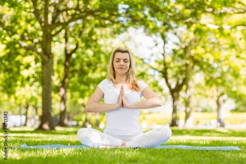 Fit blonde sitting in lotus pose in the park