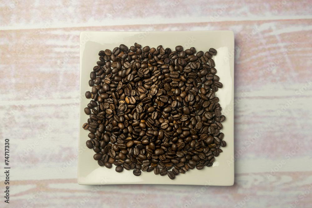 White square plate with a heap of coffee beans White square plate with a heap of coffee beans