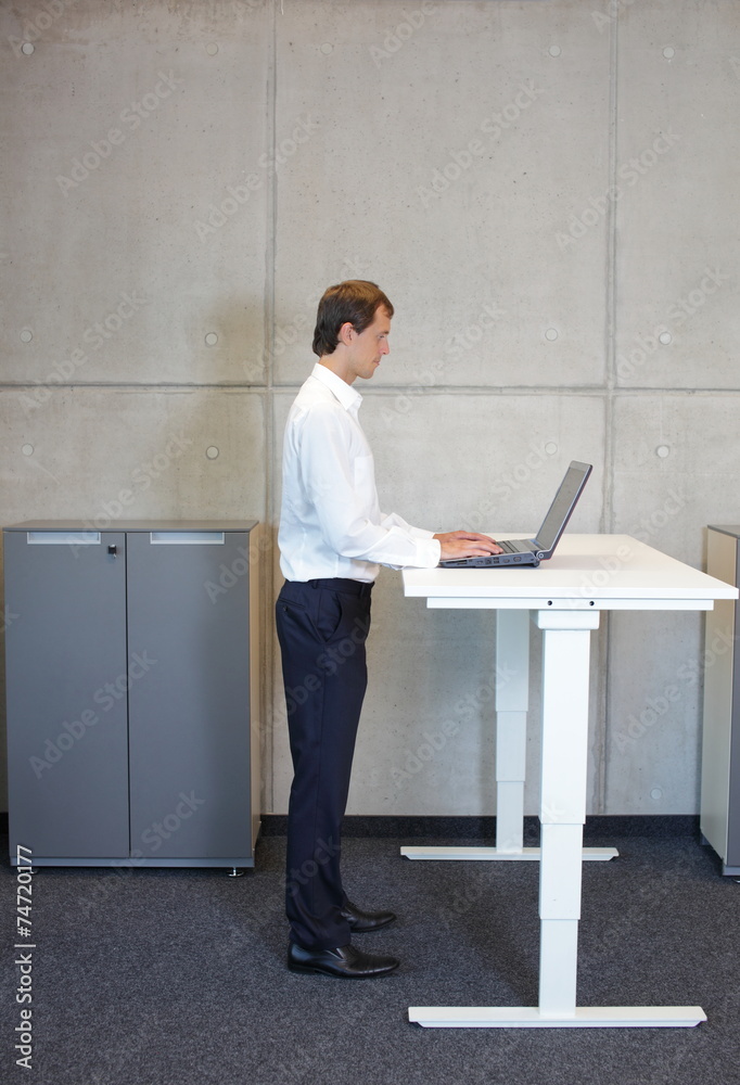 fit smart casual man standing at height adjustment table Stock Photo