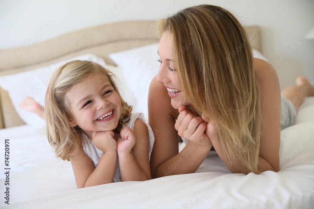Portrait of cute little girl with mommy laying on bed
