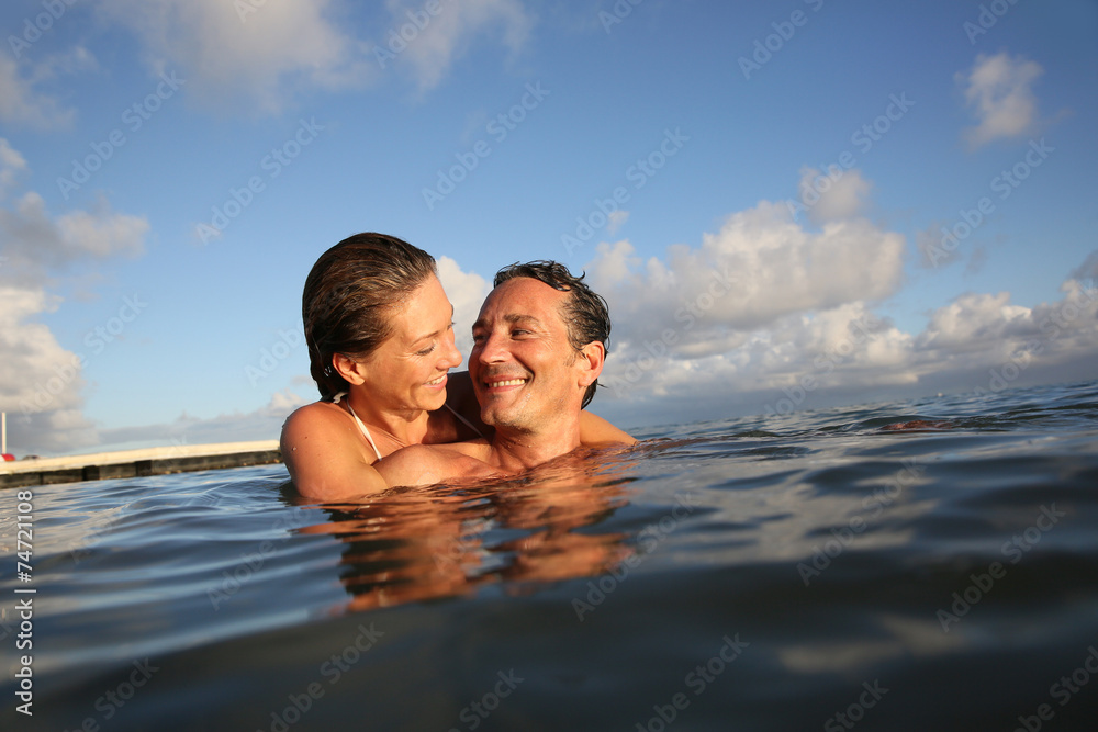 Couple swimming in sea at sunset