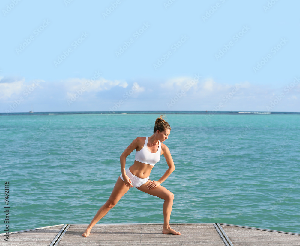 Woman doing stretching exercises in pontoon by the sea Woman doing stretching exercises in pontoon by the sea