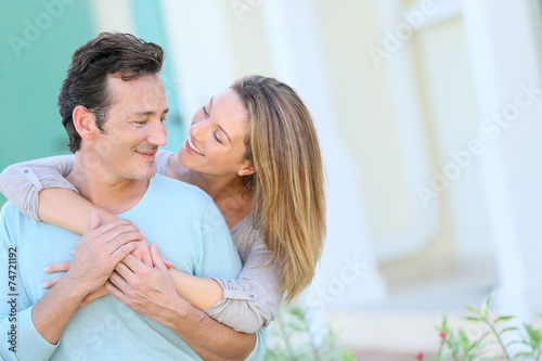 Middle-aged couple embracing in front of house