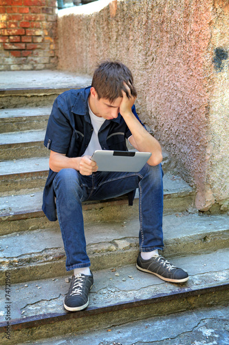 Sad Teenager with Tablet Computer © Sabphoto