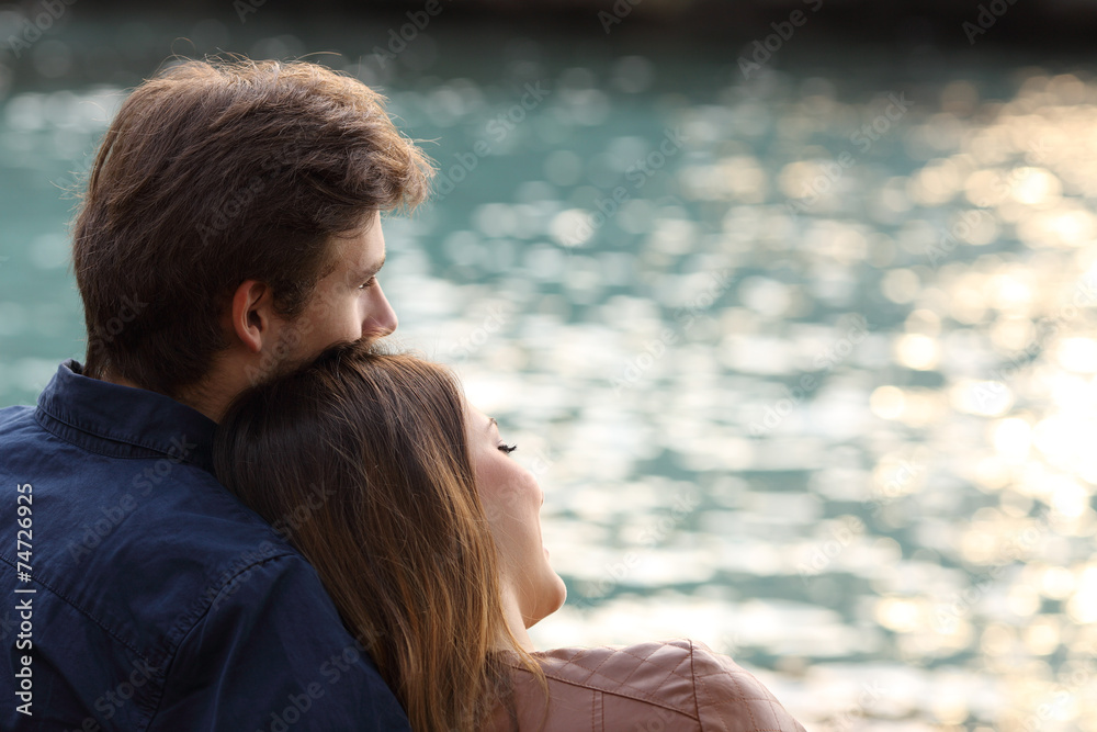 Fototapeta premium Couple hugging and watching the sea on the beach