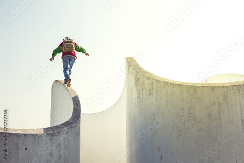 Canvas Print brave extreme man with backpack walking on a thin concrete wall
