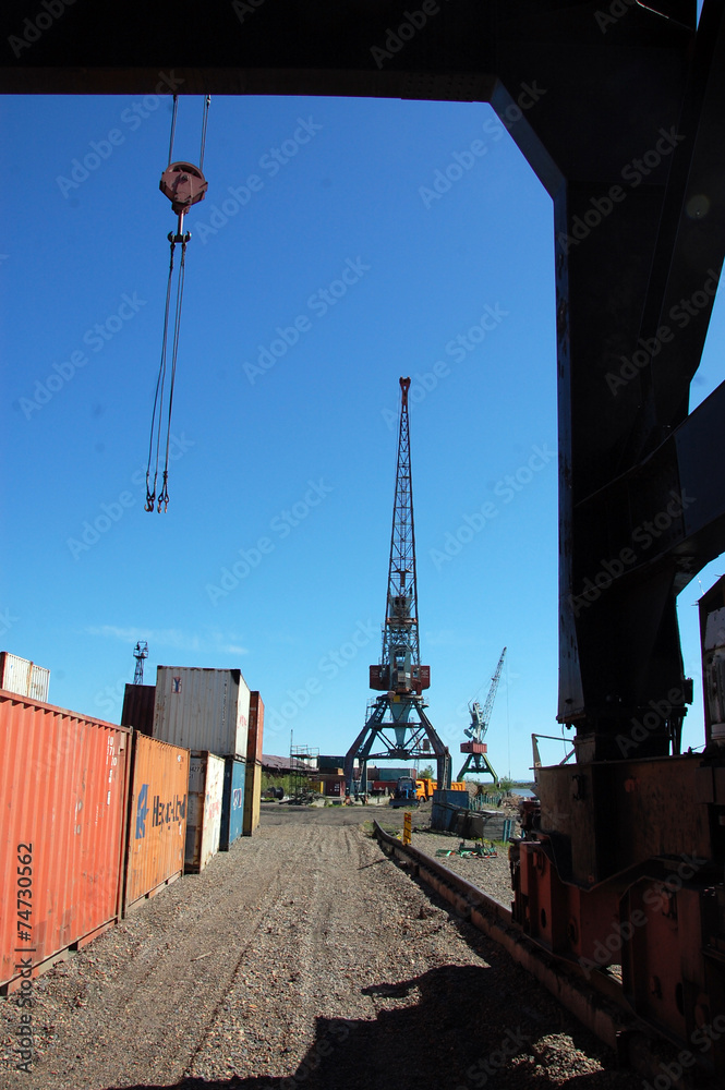 Crane loading metal container to ship at Kolyma river port