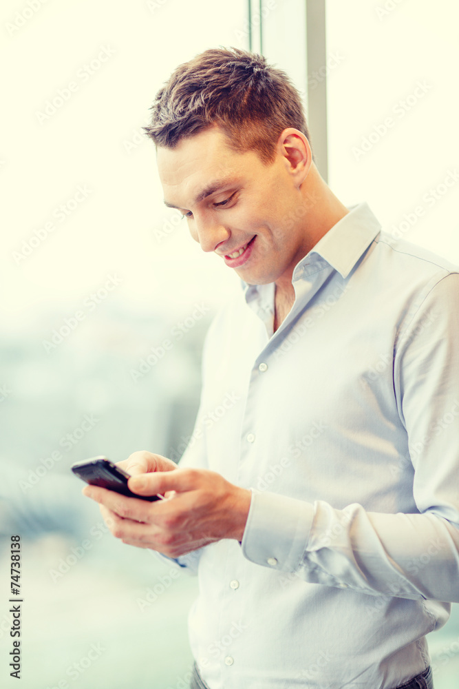 smiling businessman with smartphone in office smiling businessman with smartphone in office