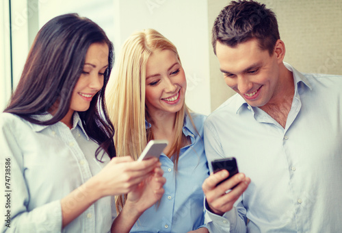 smiling business team with smartphones in office