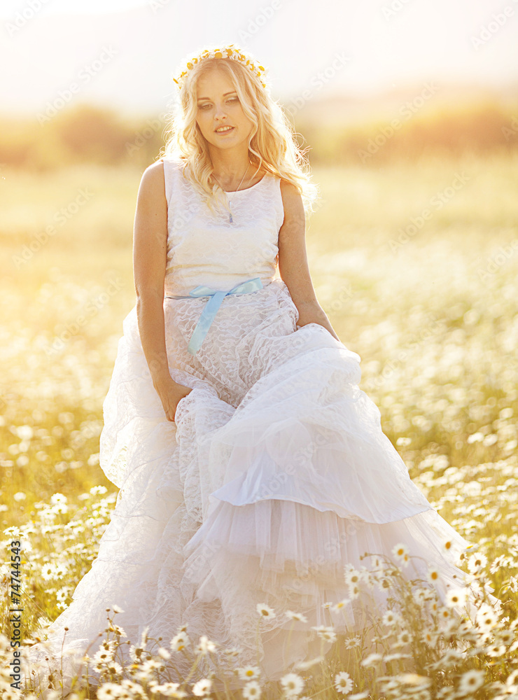 beautiful girl in a wedding dress in a field of daisies