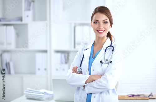Portrait of young woman doctor with white coat standing in