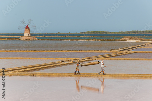 Two workers at the salt pans in Marsala carrying and heavy load. photo