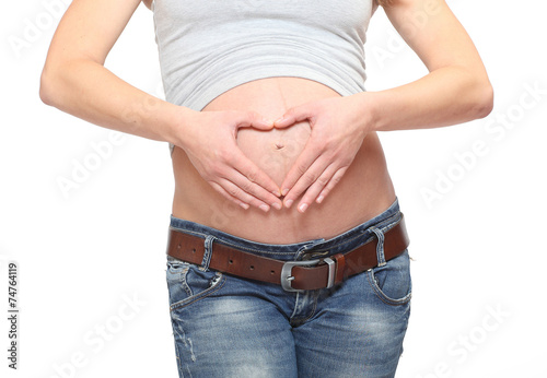 A woman's hands forming a heart symbol on pregnant belly. © Kletr