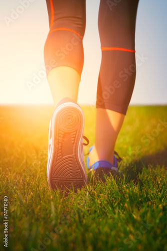 Girl running shoes closeup, green grass, woman fitness
