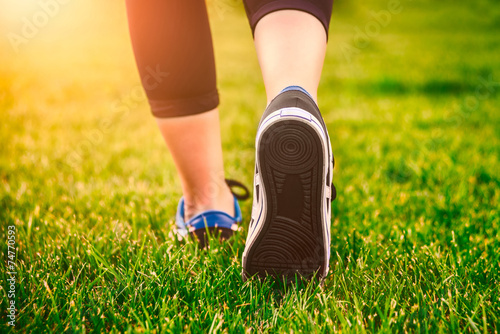 Girl running shoes closeup, green grass, woman fitness