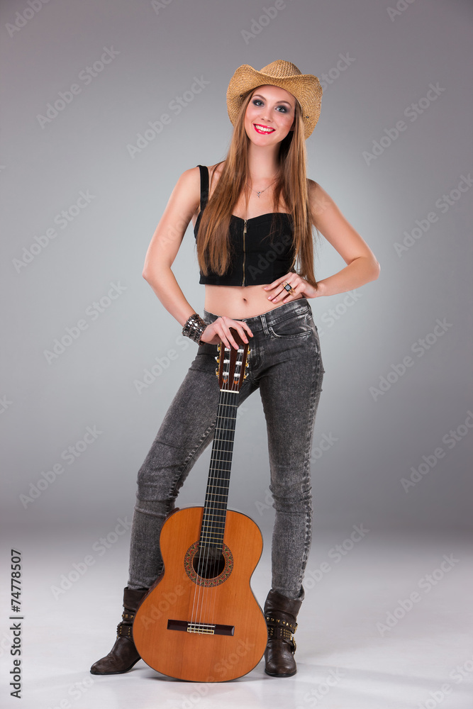 The beautiful girl in a cowboy's hat and acoustic guitar. The beautiful girl in a cowboy's hat and acoustic guitar.