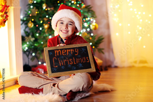 Little boy sitting near fir...