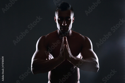 Silhouette of a muscular man praying