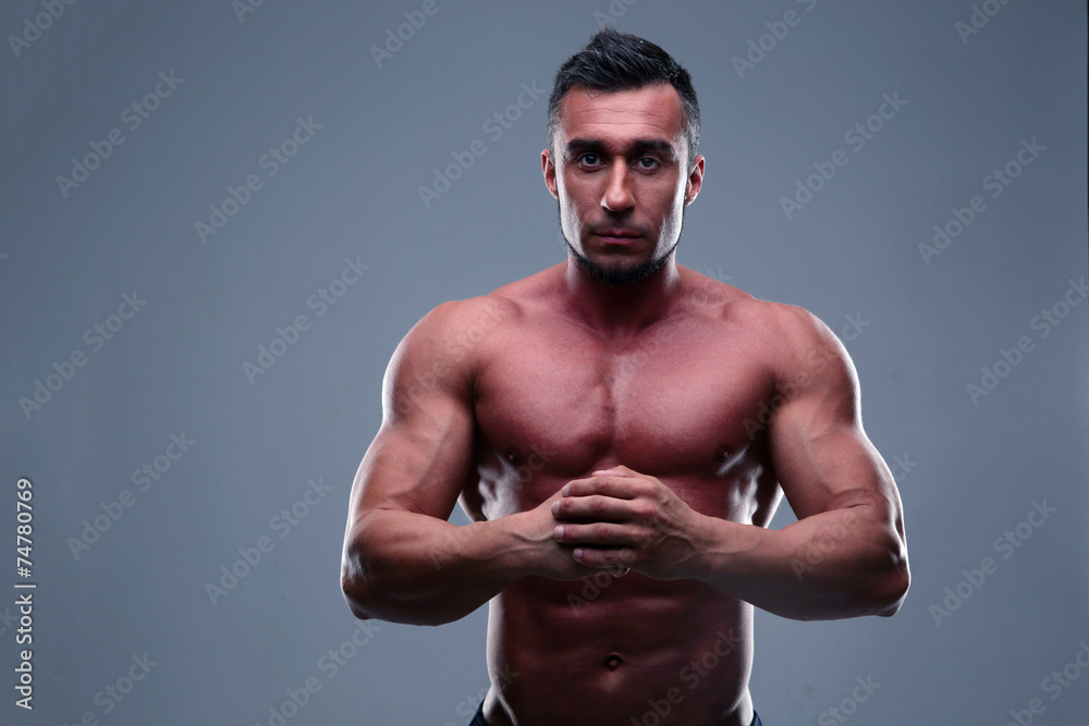 Muscular man standing over gray background