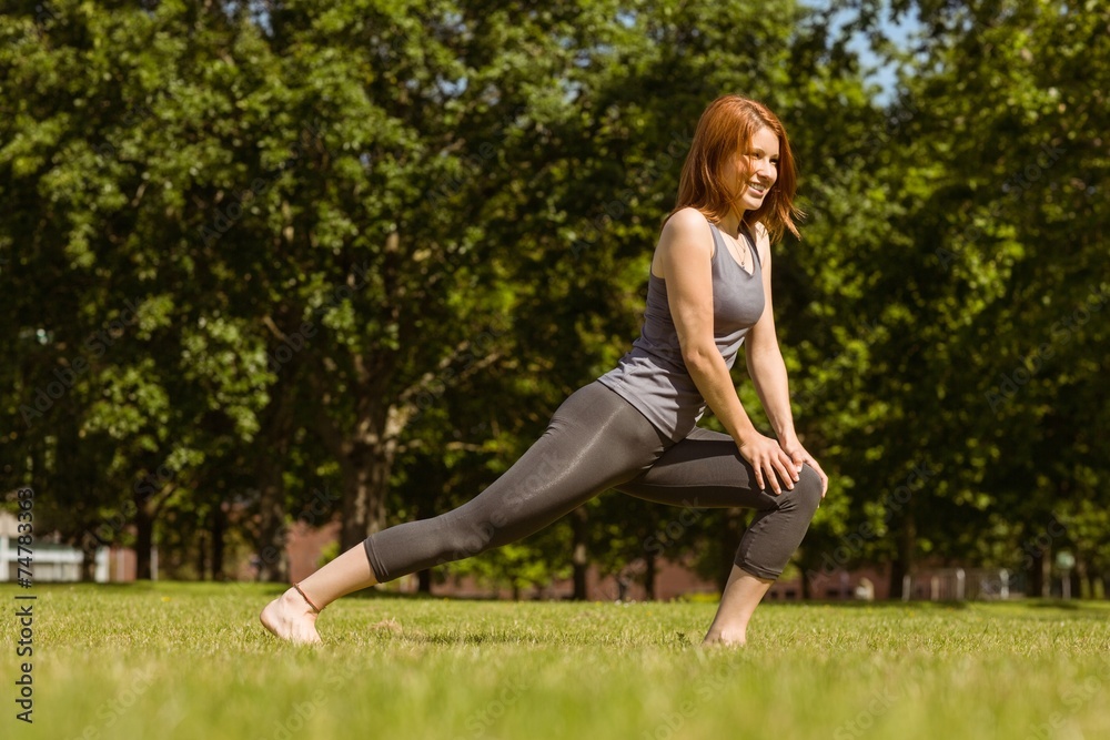 Pretty athletic redhead stretching in park Pretty athletic redhead stretching in park