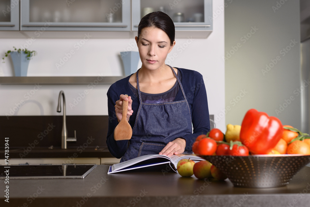 Ernste Frau in der Küche überlegt mit einem Kochbuch